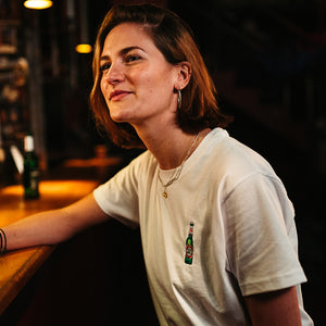 weibliches Model trägt weißes T-Shirt mit gestickter Becks Bierflasche in Bar Atmosphäre