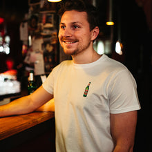 Load image into Gallery viewer, männliches Model trägt weißes T-Shirt mit gestickter Becks Bierflasche in Bar Atmosphäre