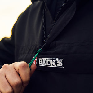 grünes Band am Reißverschluss der schwarzen Jacke mit gesticktem Beck's Logo